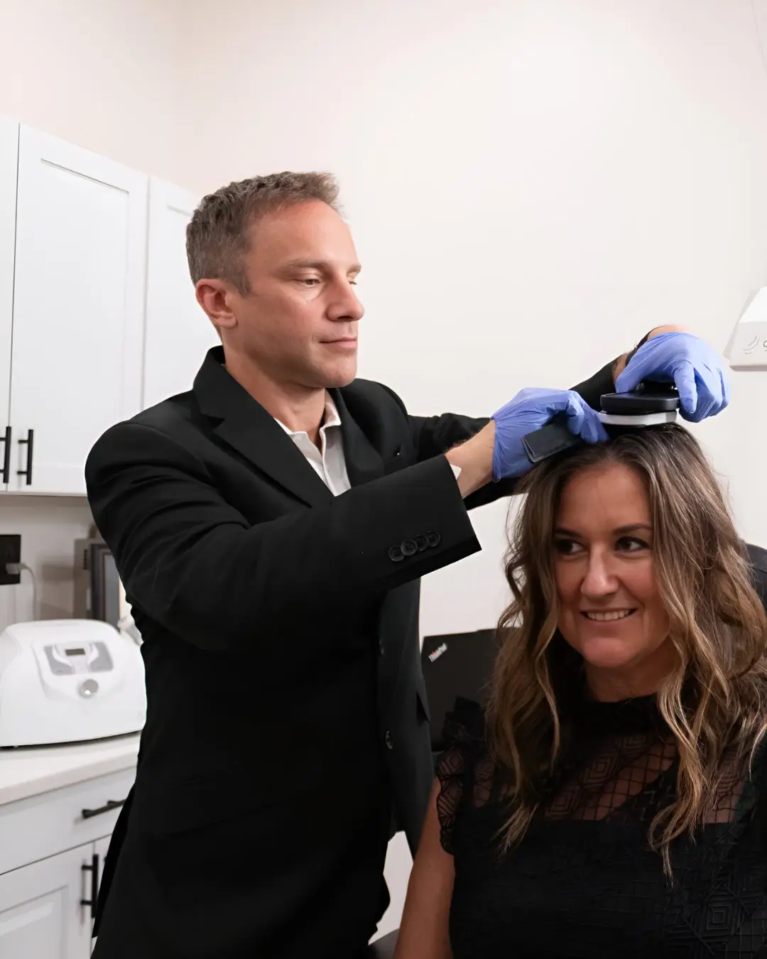 Dr. Justin Arambasick using a handheld laser hair growth device on a patient in Dayton, Ohio